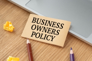 Business Owners Policy Text on A Craft Card Near A Laptop