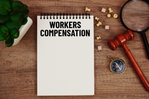 Workers Compensation Message Written on Notepad with Wood Gavel and Magnifying Glass