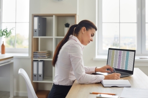 Businesswoman Reviewing Payroll Records and Worker Classifications in Her Office