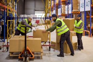 Workers in Warehouse Carefully Loading Boxes on Pallet
